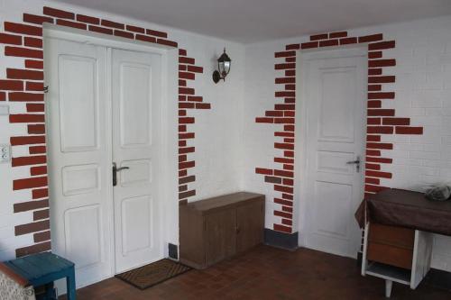 a room with two white doors and a brick wall at Guest house and Cuisine by Meri Poppins in Dedoplis Tskaro