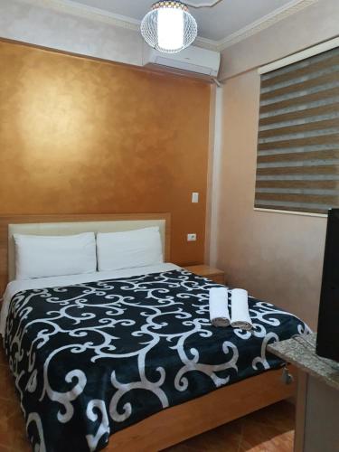 a bedroom with a bed with a black and white comforter at Kompleksi GJONI in Fier