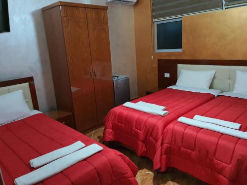 two beds in a room with red sheets at Kompleksi GJONI in Fier