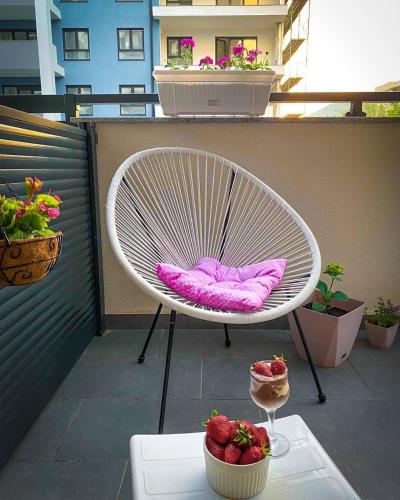 a white chair sitting on a balcony with a bowl of strawberries at Apartman Barocco in Trebinje