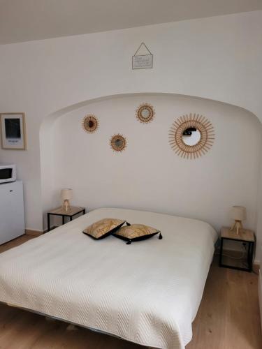 um quarto com uma cama branca e dois espelhos na parede em Le Studio 64 em Rochefort
