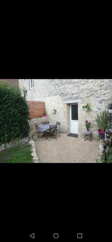 un patio avec une table et des chaises et un bâtiment dans l'établissement Petite maison, à Saint-Vigor-le-Grand