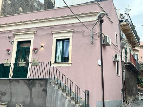 a pink house with a door and a balcony at donna serena Aci Castello in Aci Castello
