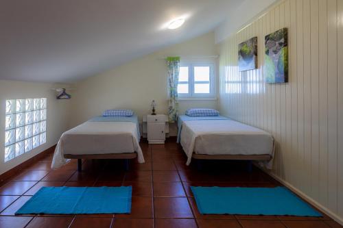 two beds in a room with blue mats on the floor at Casa Beira Mar in Mosteiros