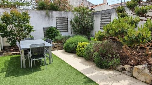 um jardim com uma mesa e cadeiras na relva em Villa d'Arçay - ADRIAE Home em LʼAiguillon-sur-Mer