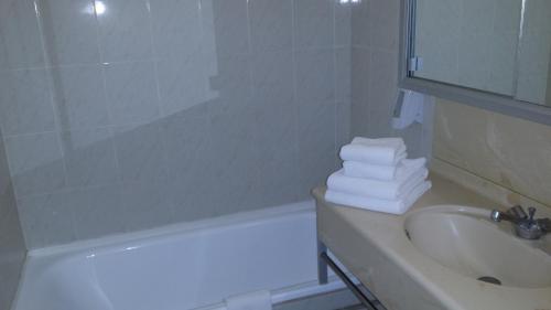 a bathroom with a sink and a bath tub with towels at La Voile D' Or in Cap d'Agde