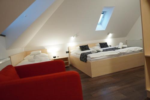 two beds in a room with a red couch at Pension Pohoda in Malá Morávka