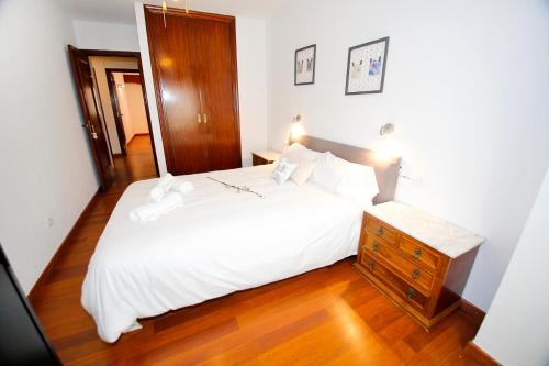 um quarto com uma cama branca e uma cómoda em madeira em Low Cost San Juan Apartment em San Juan de Alicante