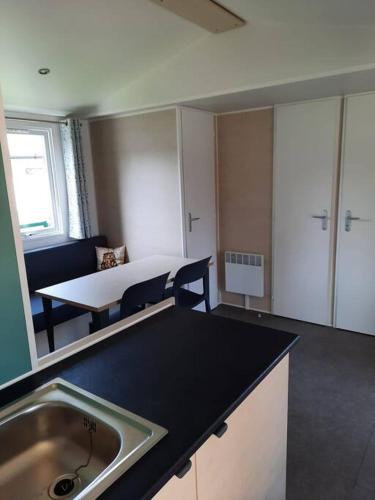 a kitchen with a sink and a table in a room at CHALETS MERCURE am Wallersee zum Vermieten in Helming