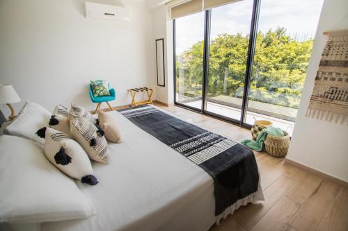 a bedroom with a large bed and a large window at Macondo Quinta Avenida Residences in Playa del Carmen