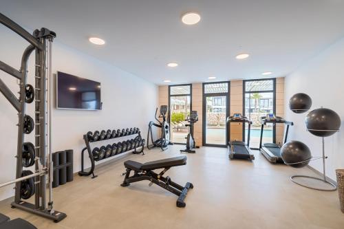 einen Fitnessraum mit Laufbändern und Kardiogeräten in einem Gebäude in der Unterkunft Barceló Nura in Sant Lluís