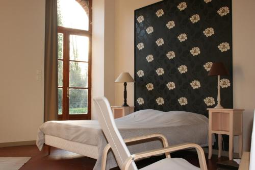 a bedroom with a bed and a chair next to a window at B&B Le Logis de Bois Renard in Saint Laurent Nouan