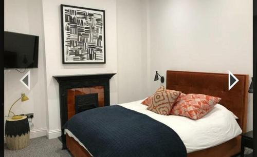 ロンドンにあるStylish home in Streatham.のベッドルーム(ベッド1台、暖炉、テレビ付)