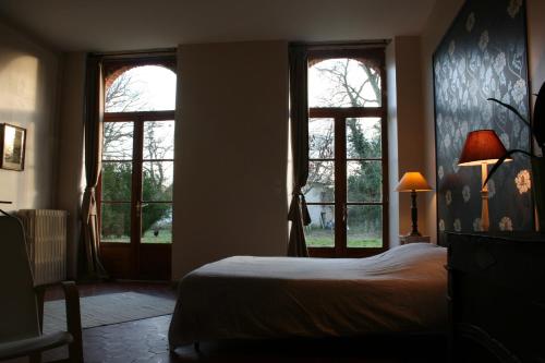 a bedroom with two windows and a bed in it at B&B Le Logis de Bois Renard in Saint Laurent Nouan