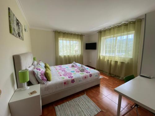 a bedroom with a bed and a table and windows at Cantinho Verde T2 in Geres