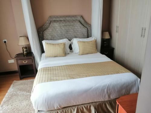 a bedroom with a large bed with white sheets and pillows at Salmiya Place 2 in Nairobi