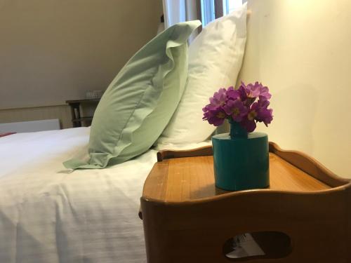 um vaso de flores roxas sobre uma mesa ao lado de uma cama em Le cottage du séquoia em Chamberet