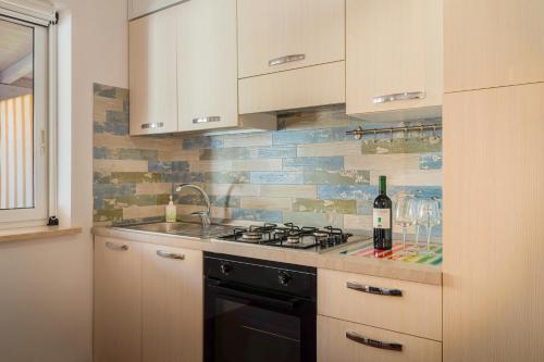 a kitchen with a stove and a bottle of wine at Casammare in Marina di Modica