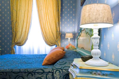 a blue bedroom with a bed with a lamp on a table at Hotel Villa San Lorenzo Maria in Rome