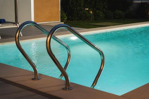 a swimming pool with a metal railing next to it at Amaré Chania Luxury Residence in Stérnai