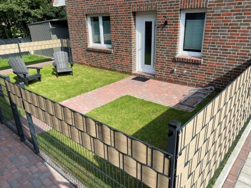 a fence in front of a house with a yard at Ankertau in Norden