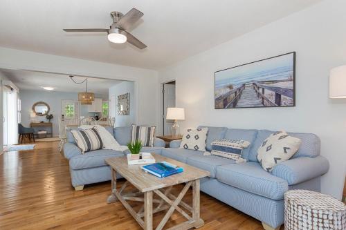 a living room with a blue couch and a table at The Emerald Owl House - Peaceful Emerald Isle Beach House w/ Luxurious Heated Pool! in Emerald Isle