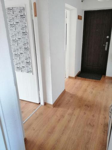 an empty room with a door and a wooden floor at Wygodny apartament blisko morza in Łokciowe