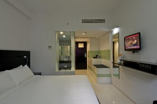 a bedroom with a white bed and a bathroom at Keys Select by Lemon Tree Hotels, Thiruvananthapuram in Trivandrum