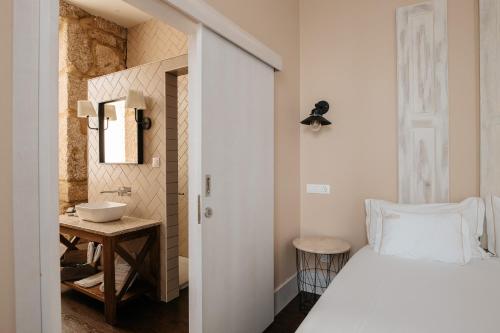 sypialnia z białym łóżkiem i umywalką w obiekcie Casa das Muralhas w mieście Covilhã