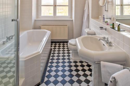 a bathroom with a tub and a toilet and a sink at Schloss Rattey in Schönbeck