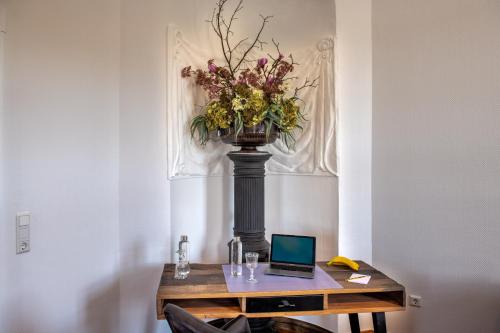a table with a vase of flowers and a laptop on it at Schloss Rattey in Schönbeck