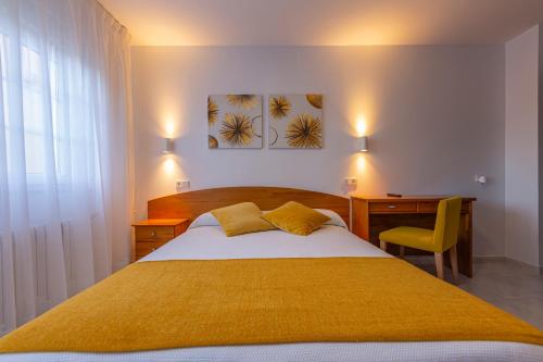 a bedroom with a large bed with a desk and a chair at Hostal Pereiriña in Cee