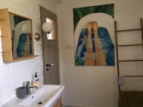 un baño con lavabo y una pintura en la pared en Domek Nikutowo, en Mrągowo
