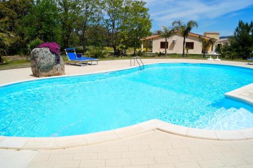 a large blue swimming pool with a chair and a house at Agriturismo Rocce Bianche - Porticato in Arbus