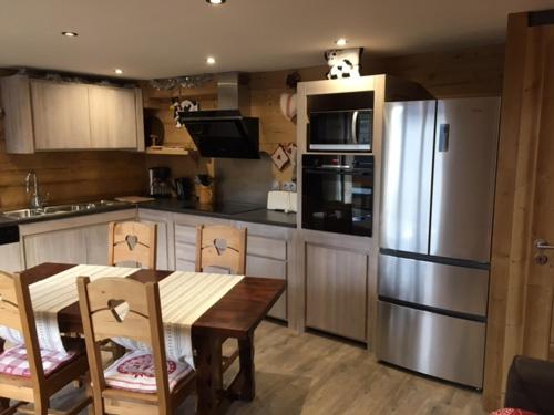 La cuisine est équipée d'une table en bois et d'un réfrigérateur en acier inoxydable. dans l'établissement Charmant T2 avec terrasse ensoleillée, proche navette, animaux admis, parking - FR-1-467-32, au Grand-Bornand