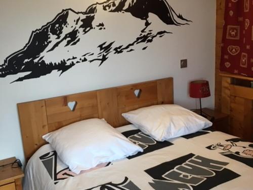 - une chambre avec un lit orné d'une fresque murale représentant la montagne dans l'établissement Charmant T2 avec terrasse ensoleillée, proche navette, animaux admis, parking - FR-1-467-32, au Grand-Bornand