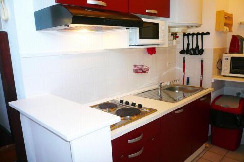 una pequeña cocina con armarios rojos y fregadero en Chez Lisette Honfleur 500m plage, en Honfleur