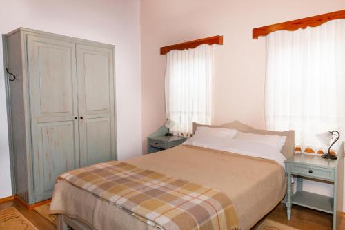 a bedroom with a bed and two windows at Zelinia in Vitsa