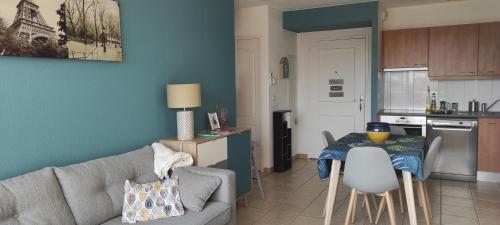 un salon avec un canapé et une table dans une cuisine dans l'établissement Appartement avec grande terrasse à 15 mn de la mer, à Saint-Estève