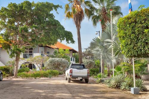 un camión estacionado frente a una casa con palmeras en Windsock Apartment Caribbean Dream, en Kralendijk