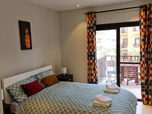 a bedroom with a bed and a balcony at Forest View Apartments in Kololi