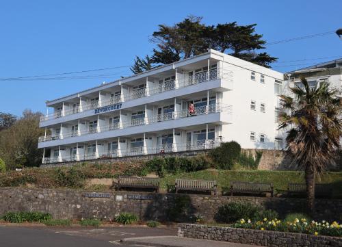 a white building with benches in front of it at Devoncourt Devoncoast SeaView Apartments in Brixham