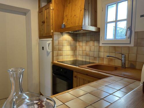 une cuisine avec des armoires en bois, un évier et une fenêtre dans l'établissement Maison avec jardin clos et terrasse, proche plage et commerces, 5 couchages, Noirmoutier-en-l'Île - FR-1-224B-83, à Noirmoutier-en-l'lle