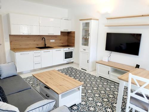 a kitchen with white cabinets and a flat screen tv at Modrý sklep 77 in Velké Pavlovice