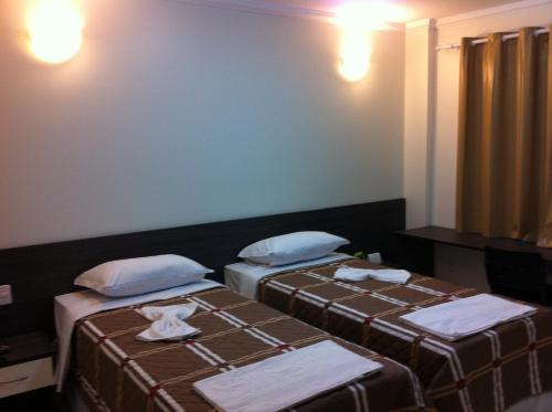 two beds in a hotel room with towels on them at Di Napoli Plaza Hotel in Gurupi