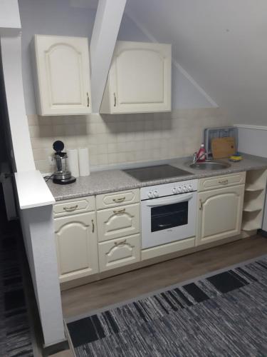a kitchen with white cabinets and a stove at 1 Zimmer Wohnung für 1-2 Gäste in Gößnitz