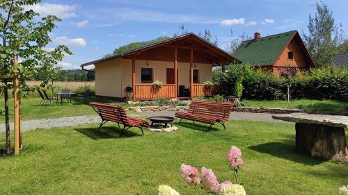 un grupo de bancos en un patio con una casa en Chaty u rybníka Brodský, en Červený Kostelec