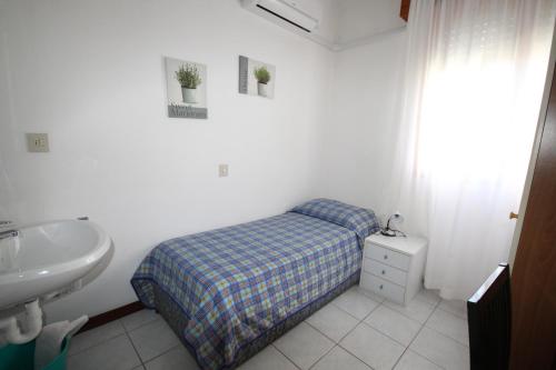 a small bedroom with a bed and a sink at Hotel Zen in Lignano Sabbiadoro