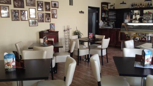 a restaurant with black tables and white chairs at Hanna Szobái in Tarcal