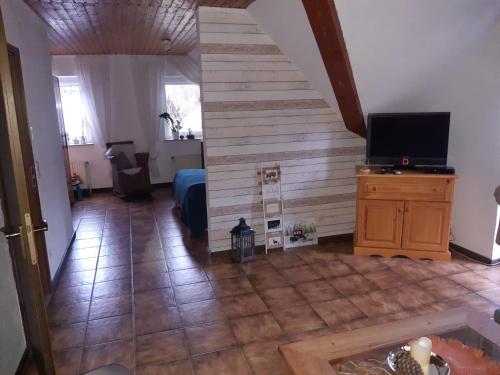 ein Wohnzimmer mit einer Treppe und einem TV in der Unterkunft Urlaub auf dem Bauernhof in Netphen